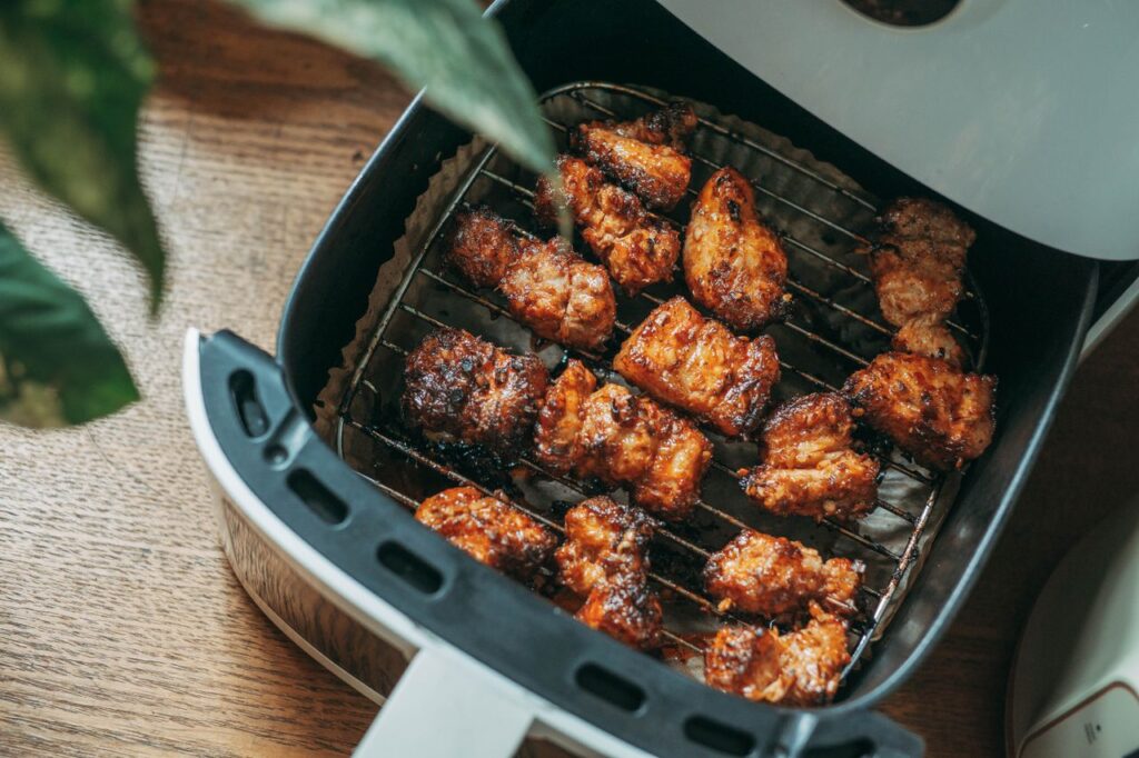 Otwarty air fryer z kawałkami przyrumienionego mięsa na ruszcie